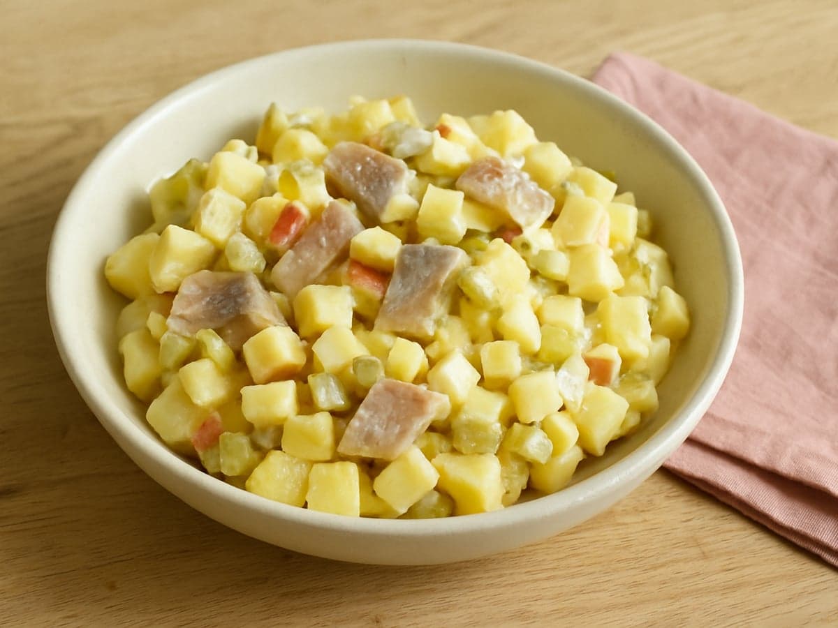 Aardappelsalade met haring en appel in een schaal