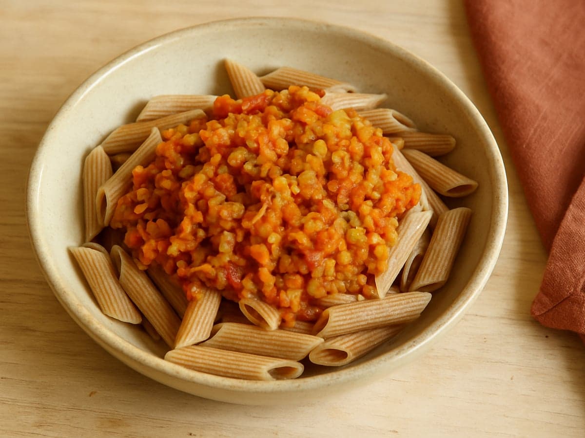 Pasta met linzenbolognese en wortel in een schaal